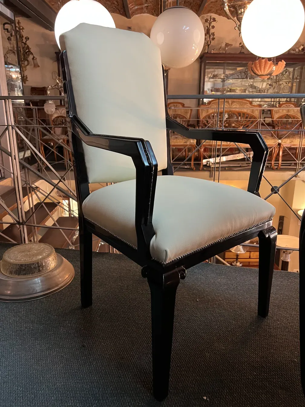 Sillón de escritorio antiguo con asiento blanco y brazos negros en un ambiente clásico.