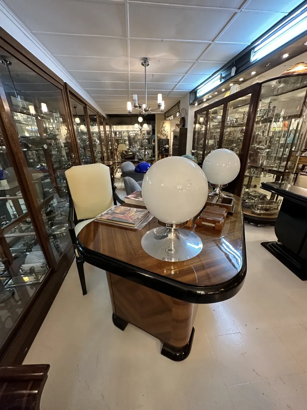 Antique desk chair in a decorative setting with lamps and display cases.