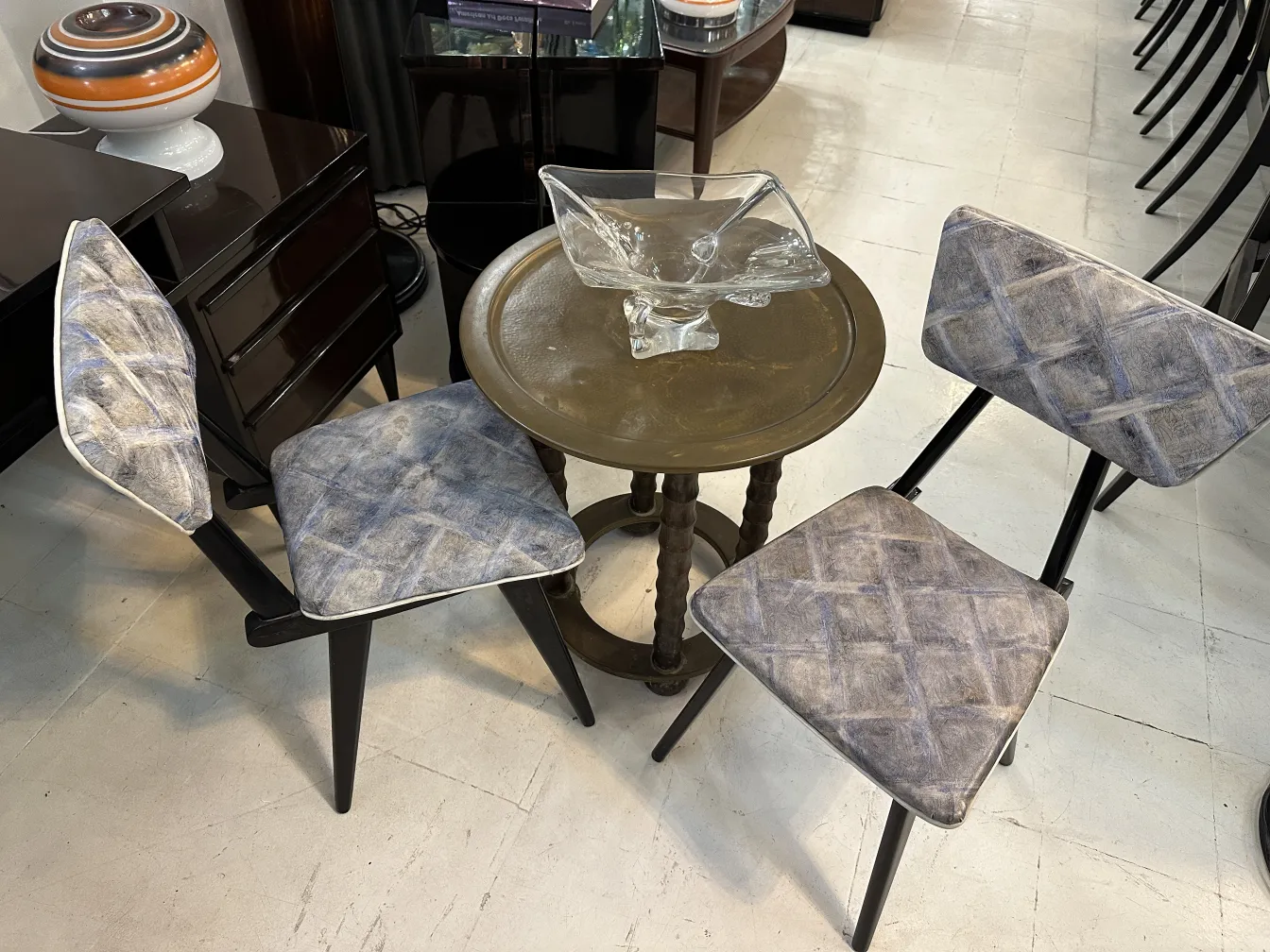 Due sedie antiche con cuscini decorativi in un ambiente elegante, accanto a un tavolo rotondo.