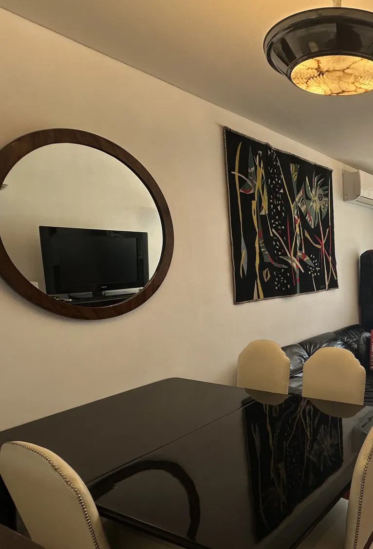 Sei sedie antiche da pranzo in un ambiente accogliente ed elegante, con uno specchio rotondo e un'opera d'arte colorata sulla parete.