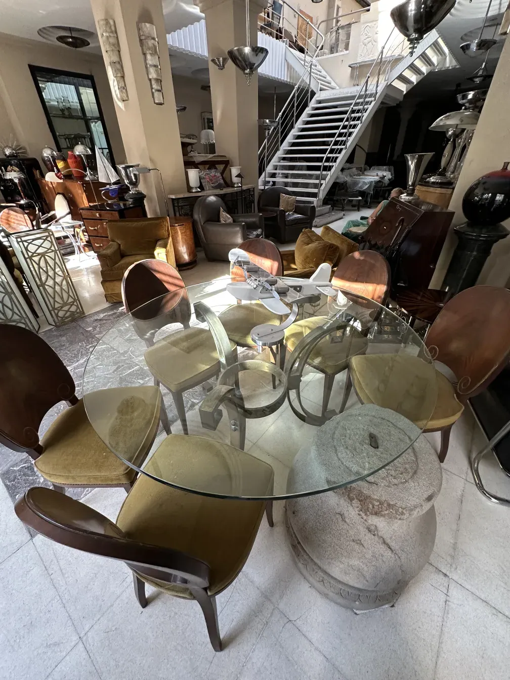 تشكيلة من 12 كراسي قديمة جانسين حول طاولة دائرية، مع أجواء مريحة.