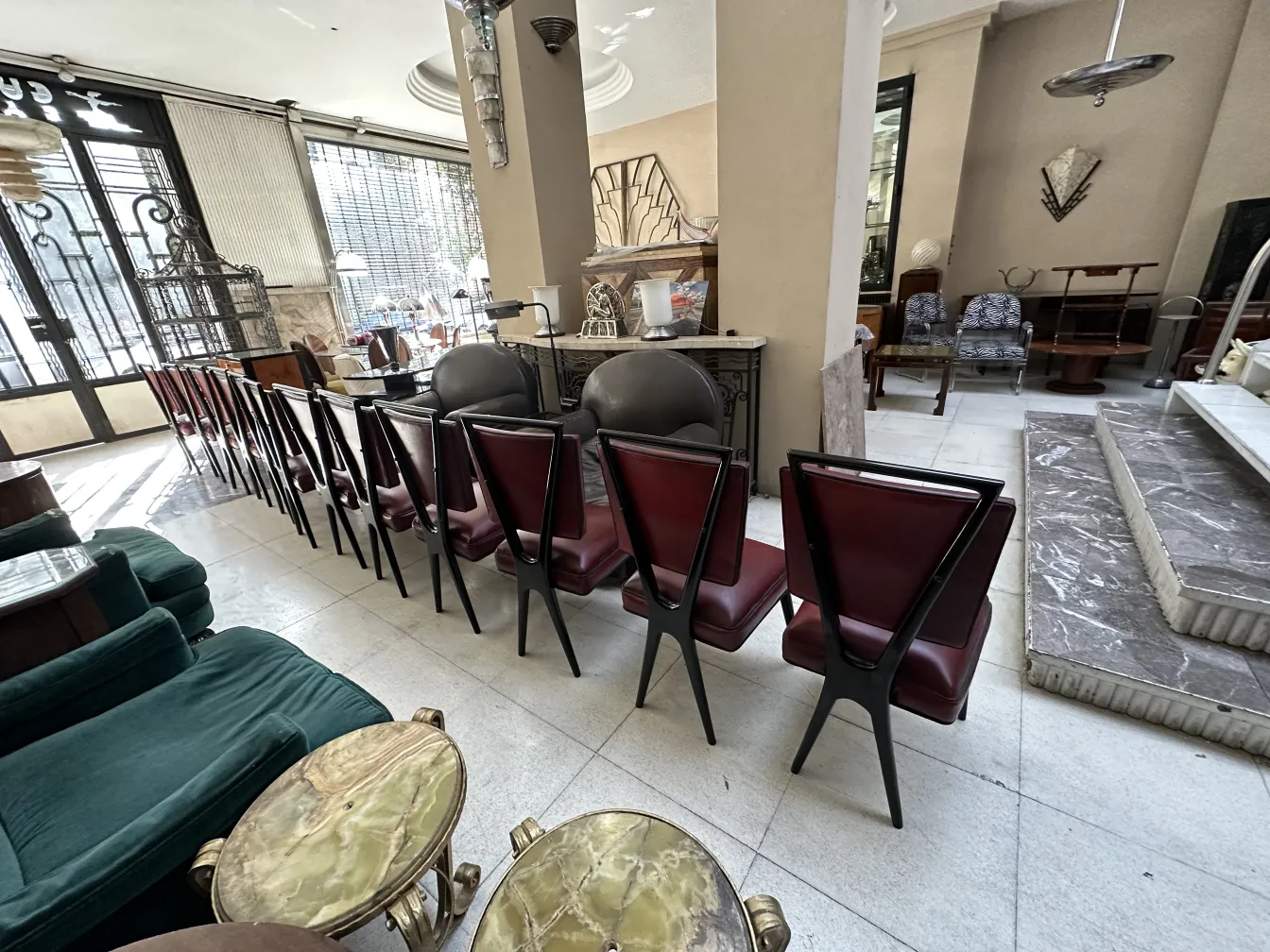 Ein Set aus 12 antiken Stühlen mit dreieckigen Rückenlehnen und rotem Polster in einem eleganten antiken Ambiente.