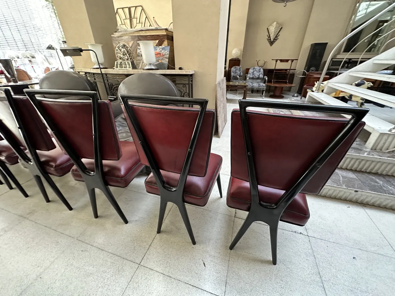 Vista traseira de 12 cadeiras antigas com estofado elegante em um ambiente de antiguidades