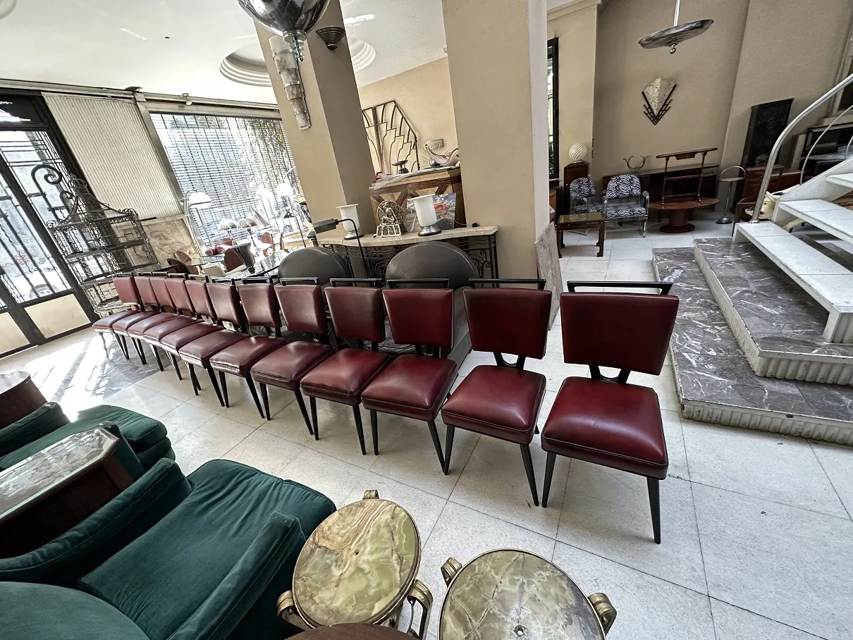 Vista de 12 sillas antiguas en una habitación luminosa con otras antigüedades alrededor.