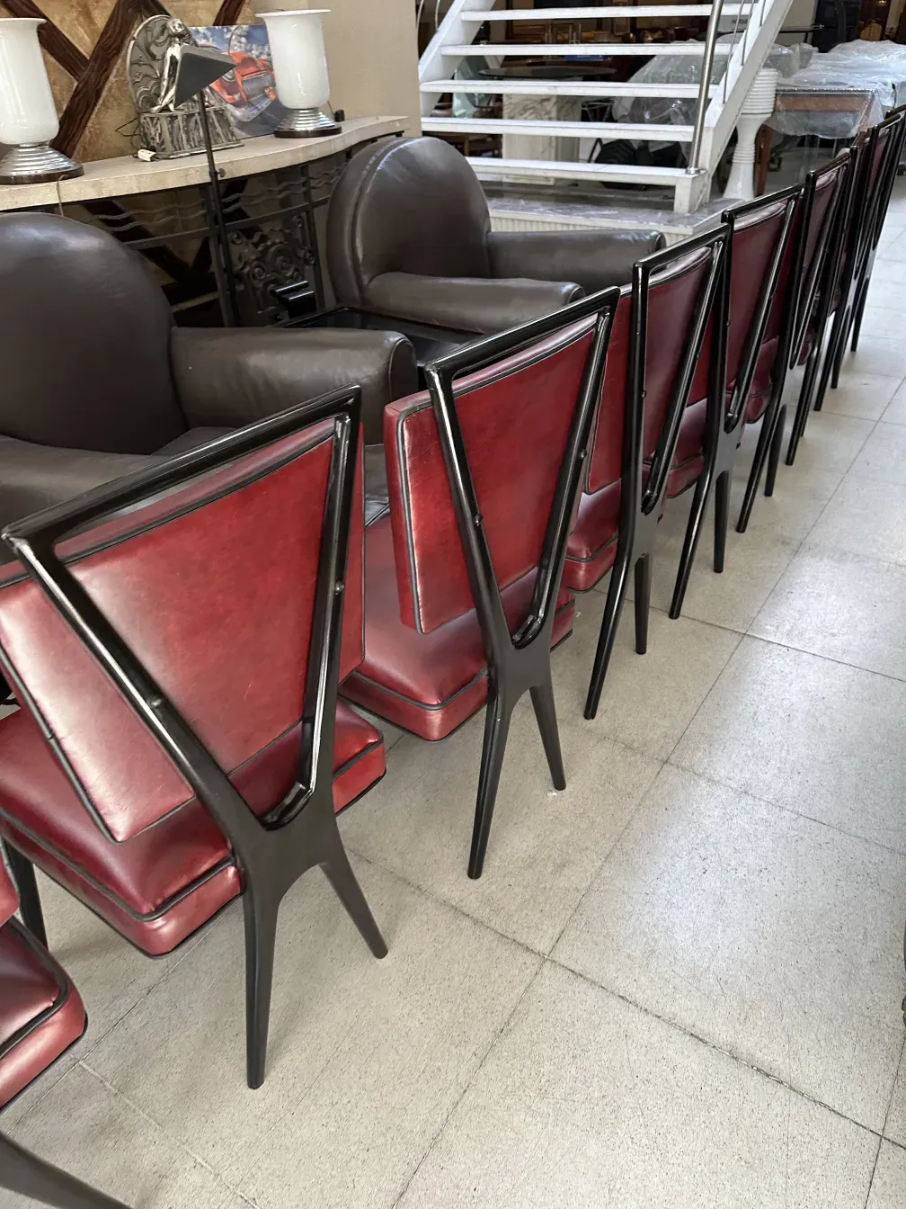 Dodici sedie antiche in stile classico con seduta rossa, disposte accanto a un tavolo.