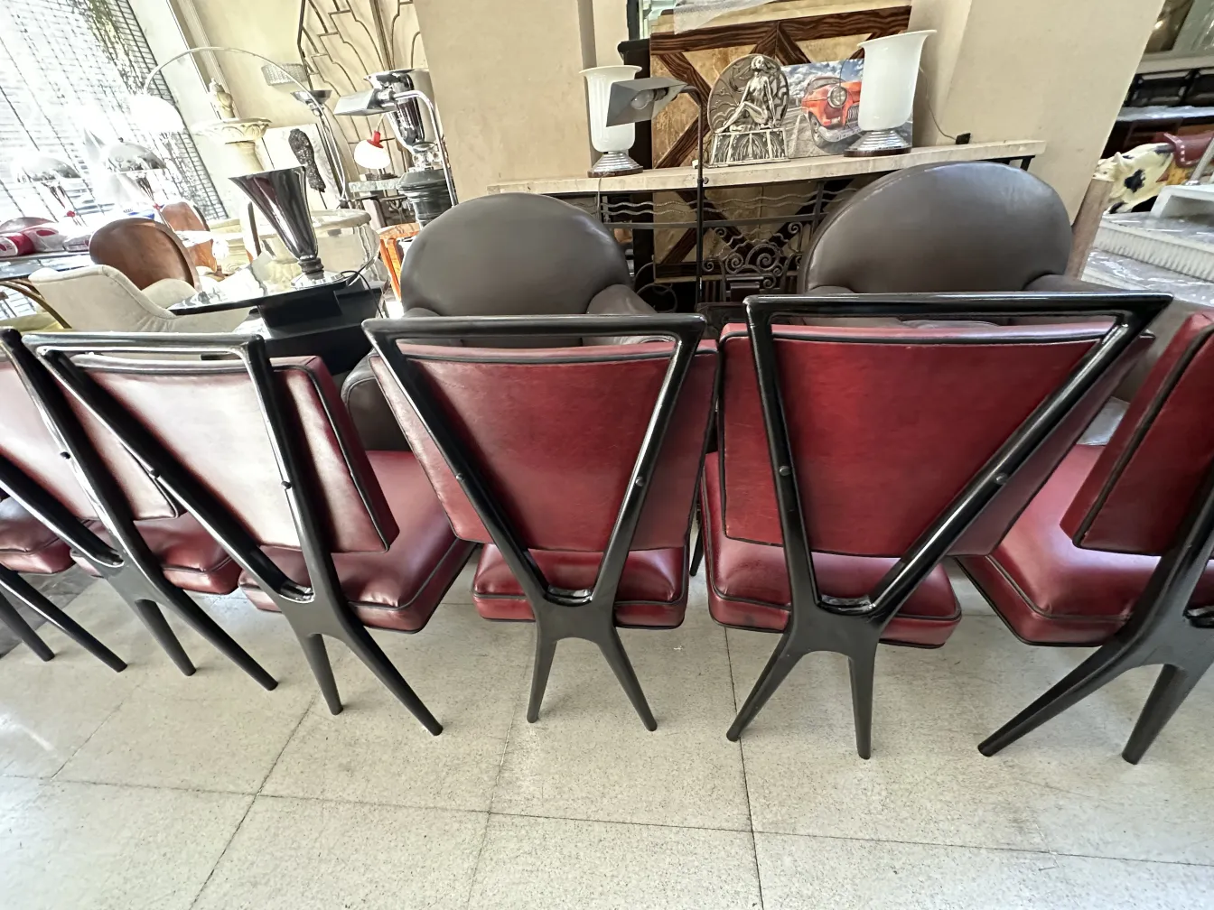 Vista de la parte trasera de 12 sillas antiguas de comedor en un ambiente elegante. Muestra detalles de diseño.