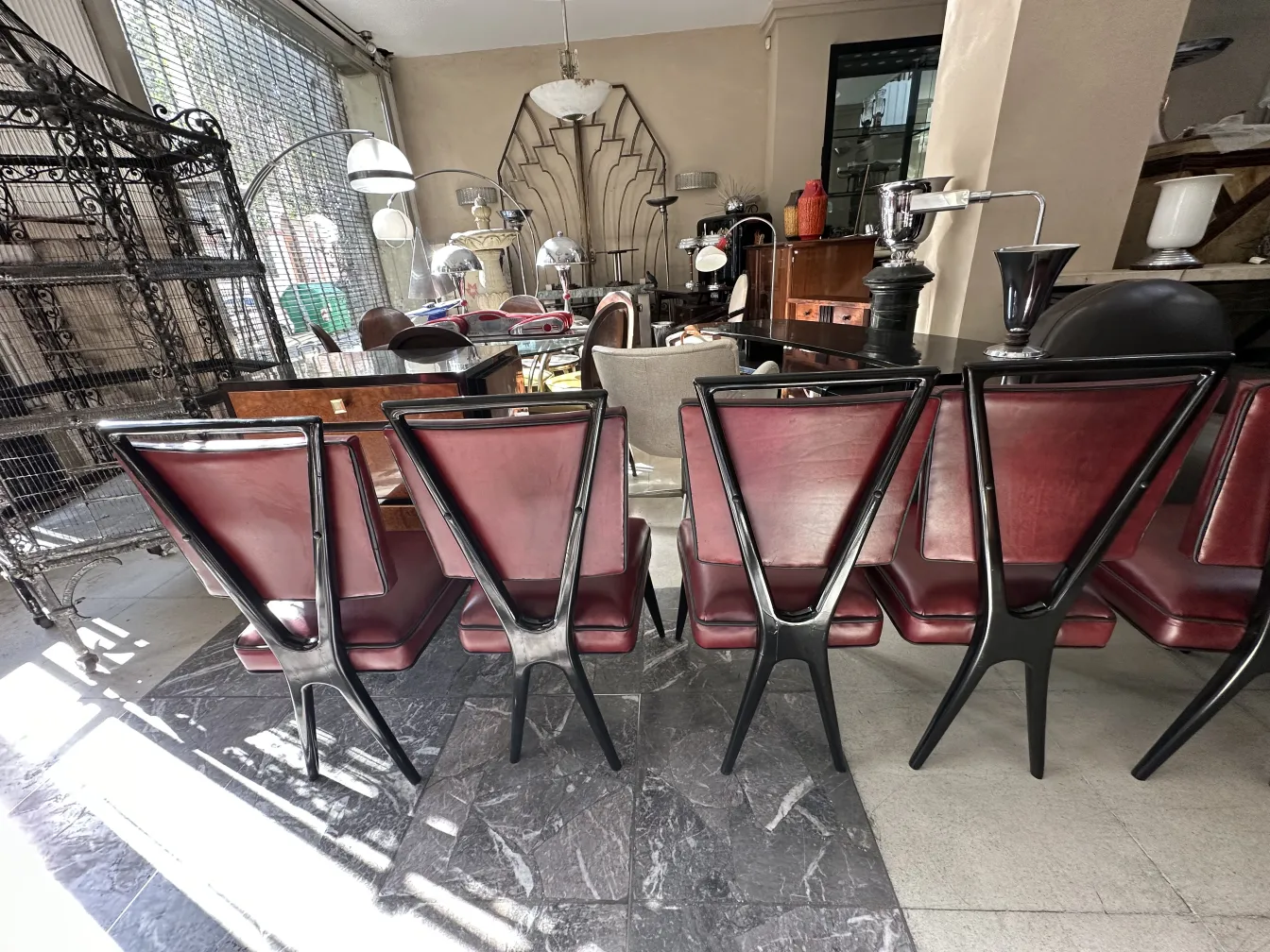 View of 12 antique chairs with stylish legs in a modern setting, surrounded by elegant lighting.