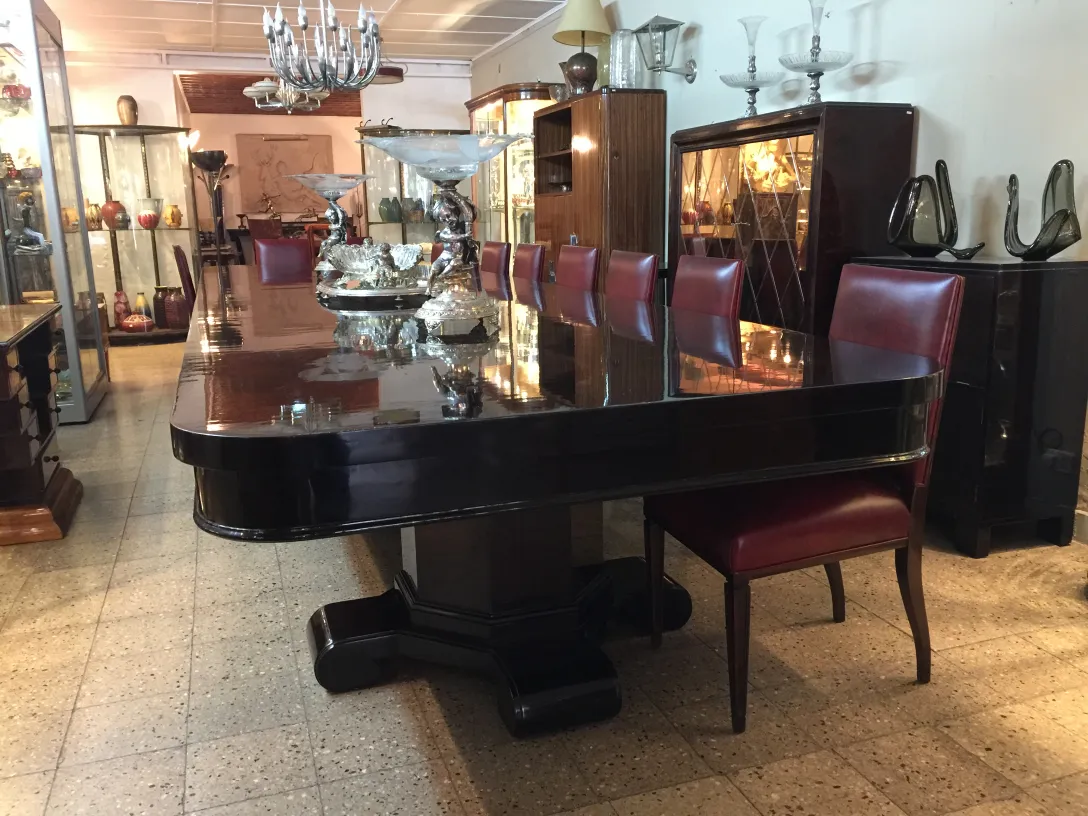 View of 12 elegant antique chairs around a shiny table in a cozy setting.