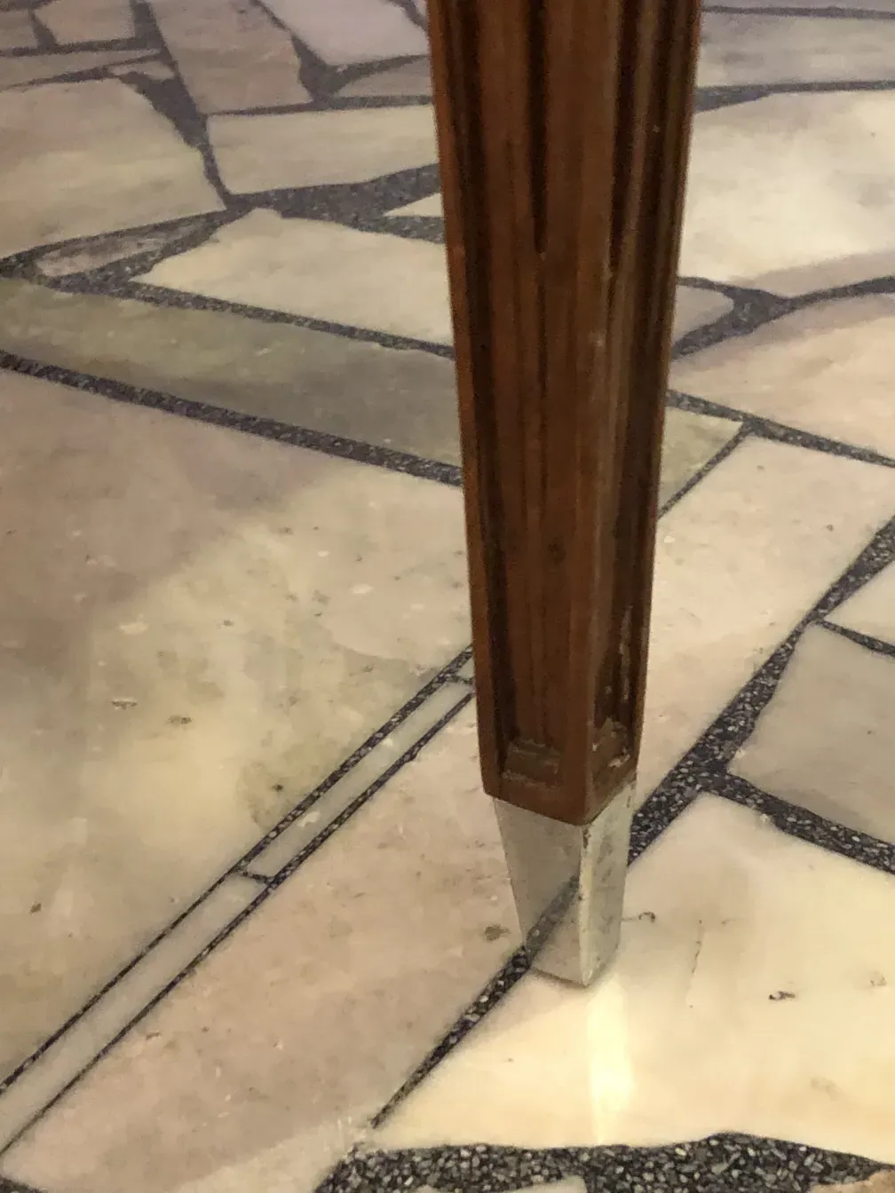 View of the legs of 12 antique chairs on a mosaic floor