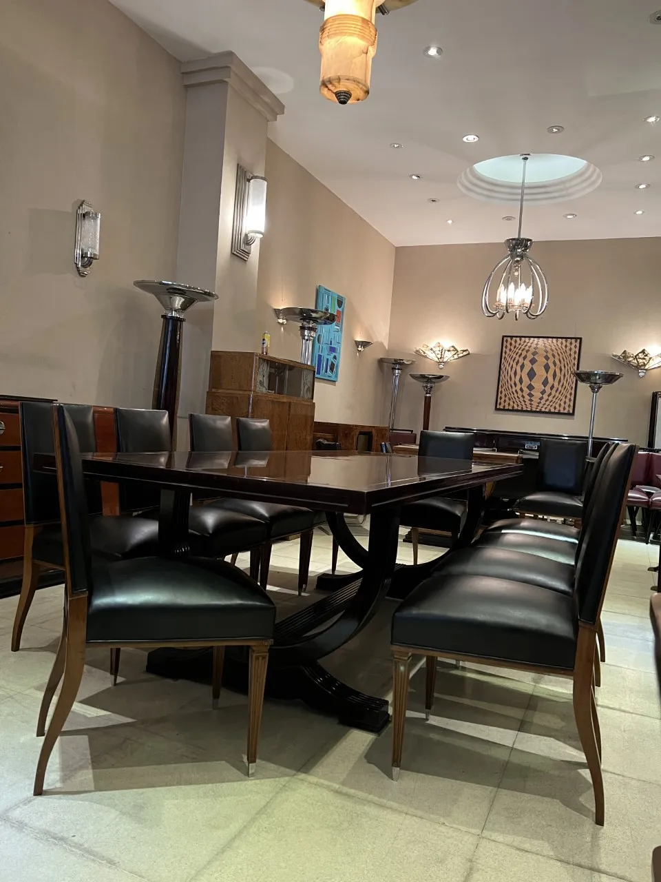 Doze cadeiras antigas elegantes distribuídas em torno de uma mesa de jantar moderna.