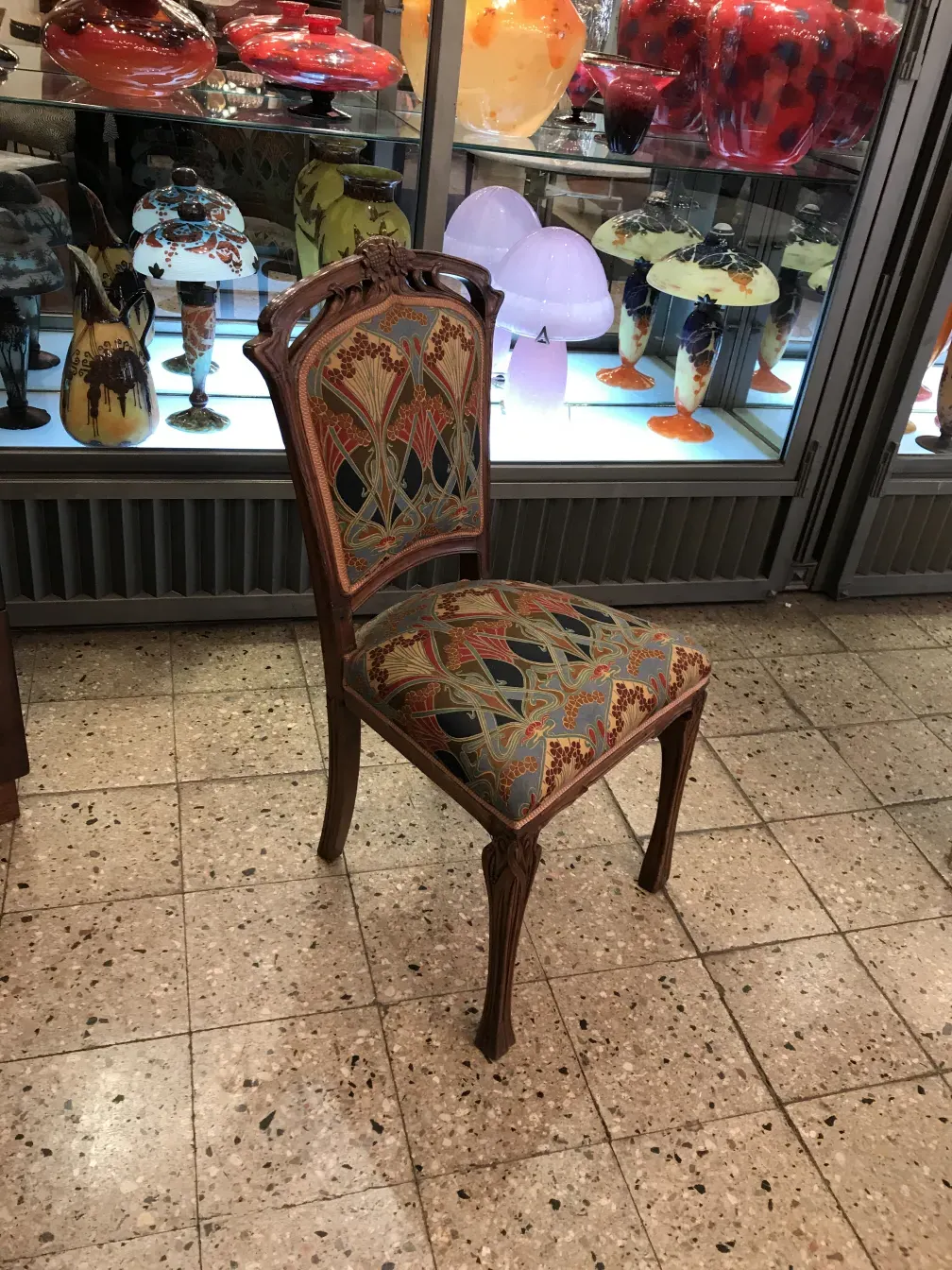 Antique decorative chair with colorful design, background with glass displays.