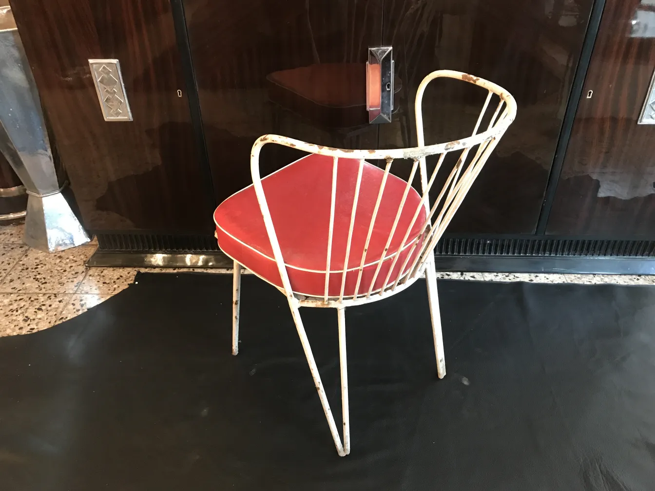 Antique garden chair with a red seat in a modern setting.