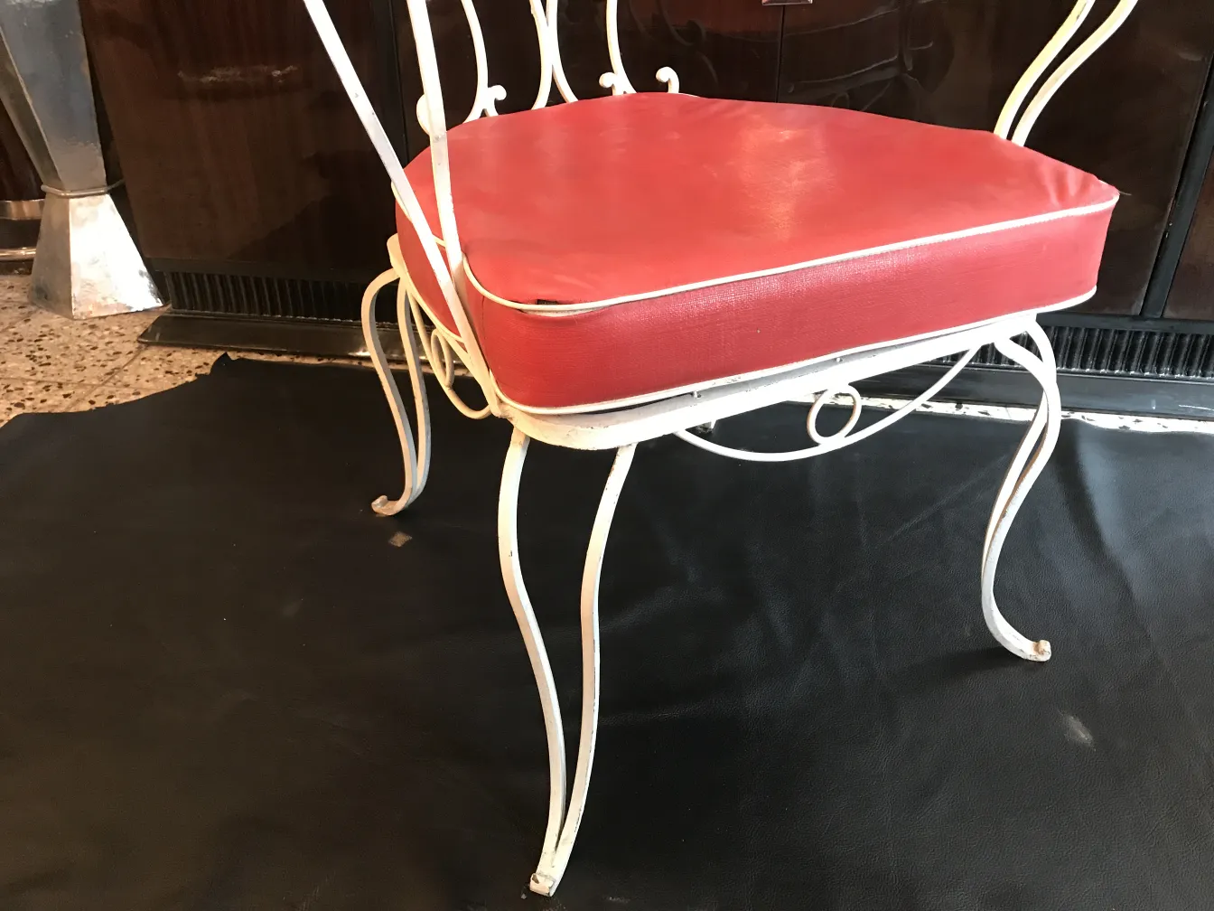 Antiker Garten-Sessel mit rotem Kissen in einem gemütlichen Ambiente