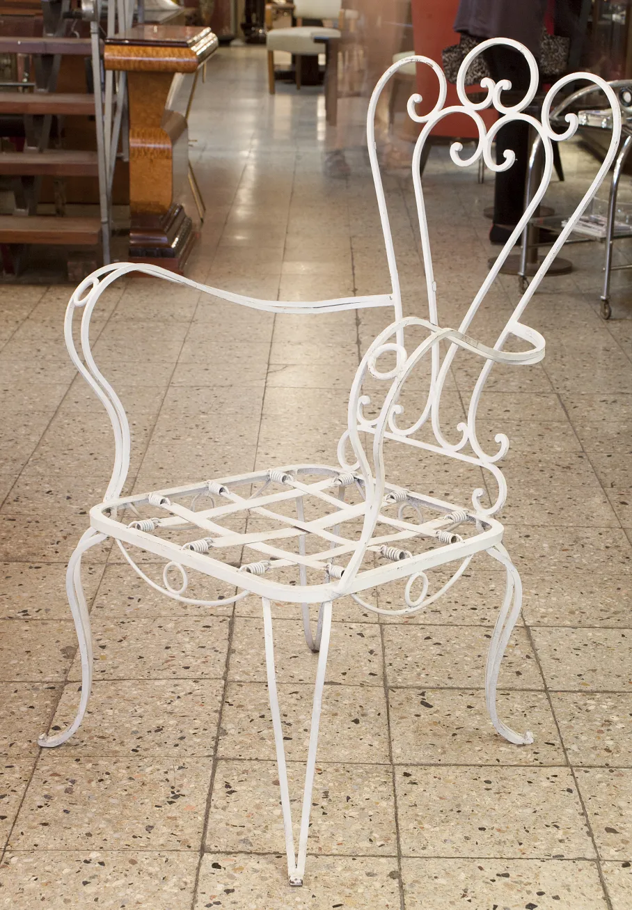 Sillón de jardín antiguo de color blanco, diseño elegante con brazos curvados, en un ambiente acogedor.