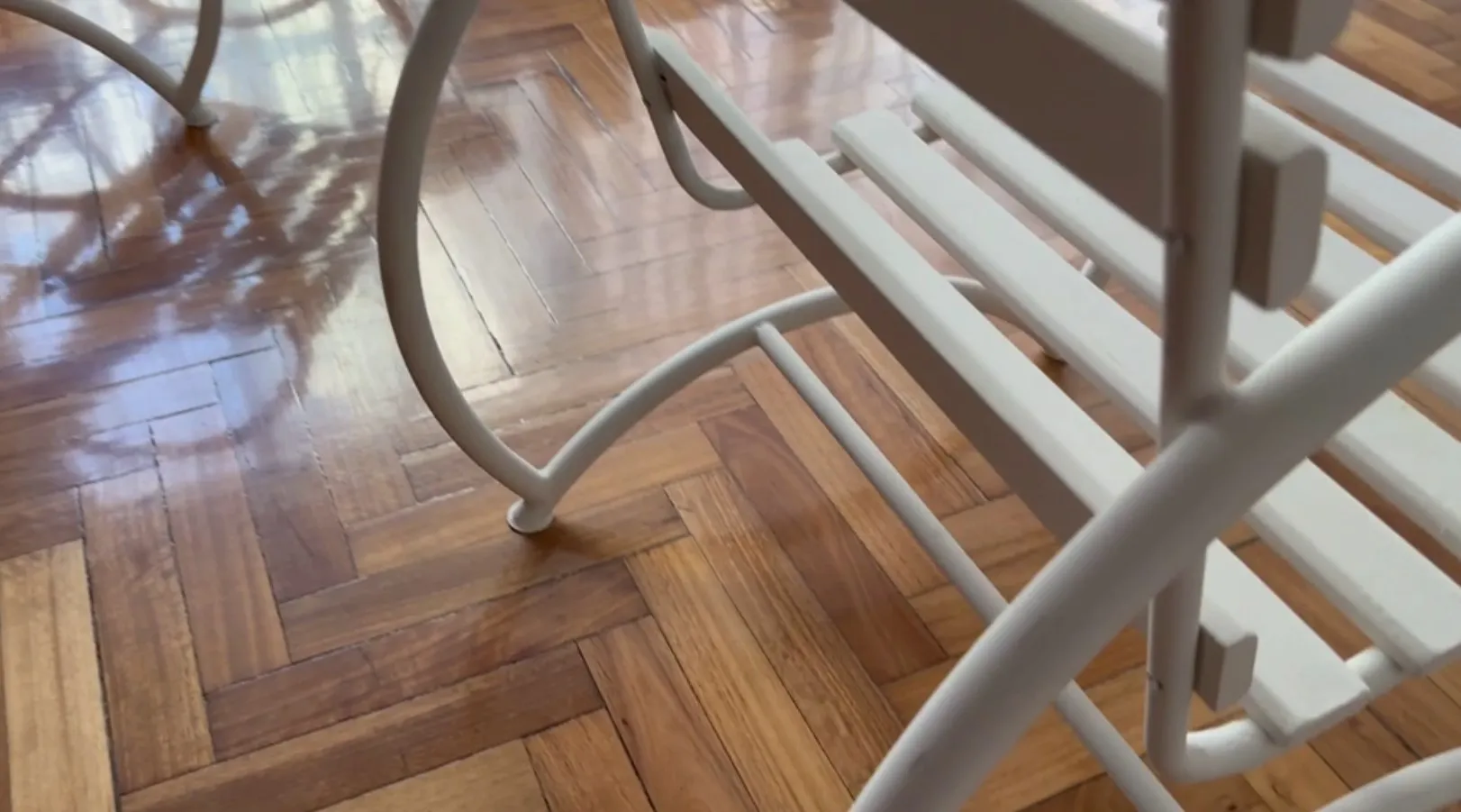 Vue de 2 fauteuils de jardin anciens avec une finition claire, sur un sol en bois brillant.