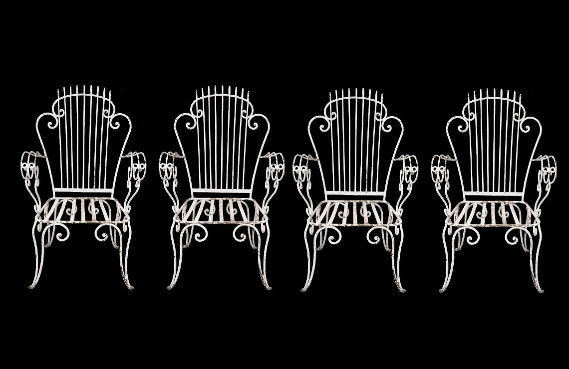 Four antique garden armchairs on a black background