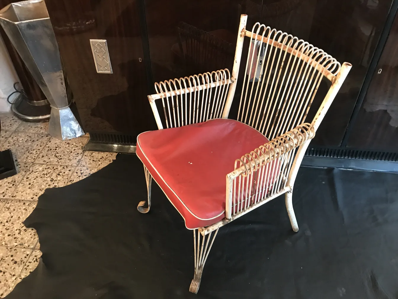 Vier antike Garten-Sessel mit roten Kissen in einem klassischen Umfeld.