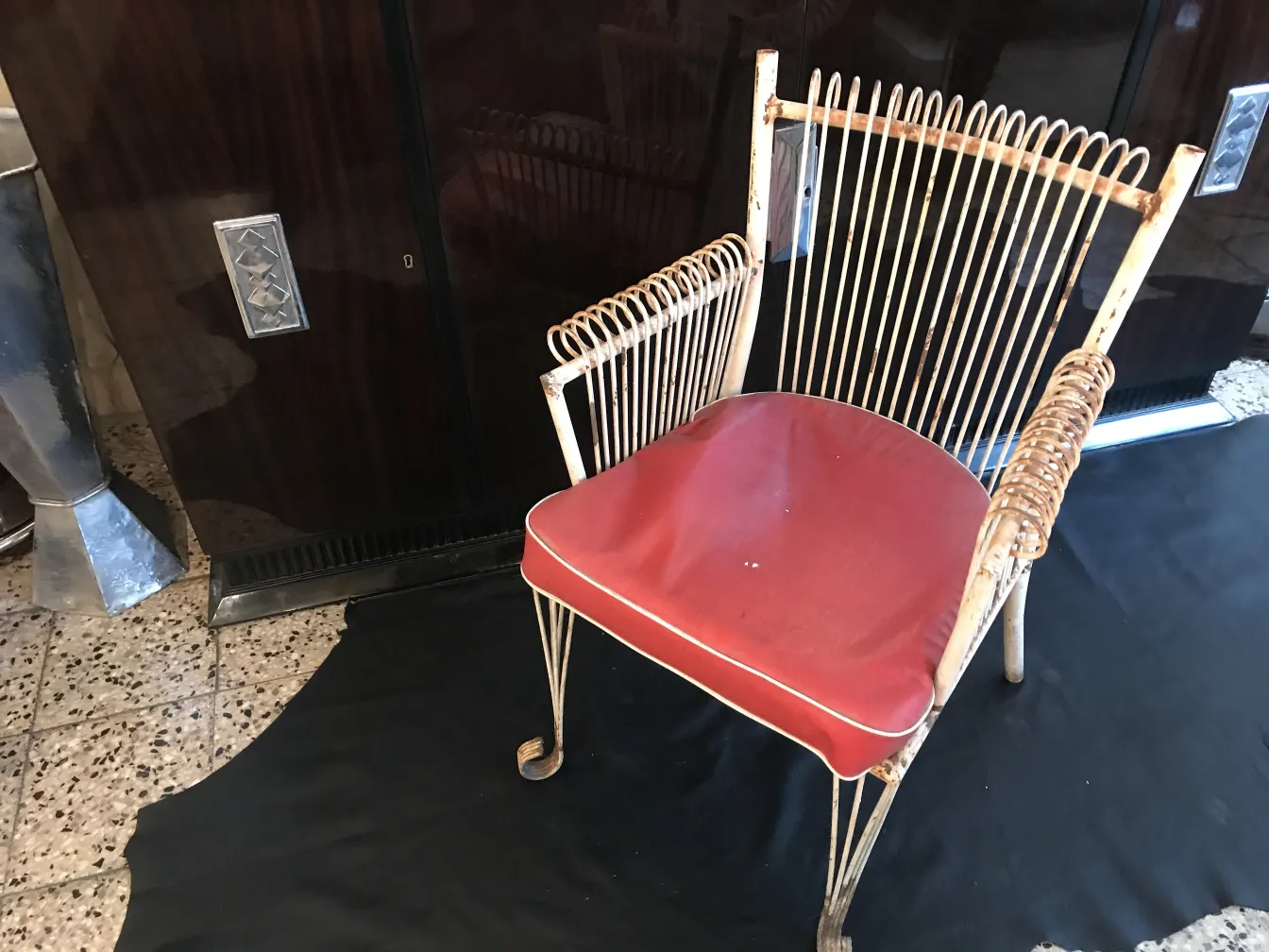 Quatro poltronas de jardim antigas com almofadas vermelhas em um ambiente elegante.