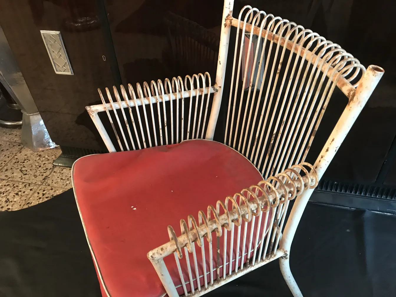 Poltronas de jardim antigas com estrutura branca e almofada vermelha, ambiente clássico.