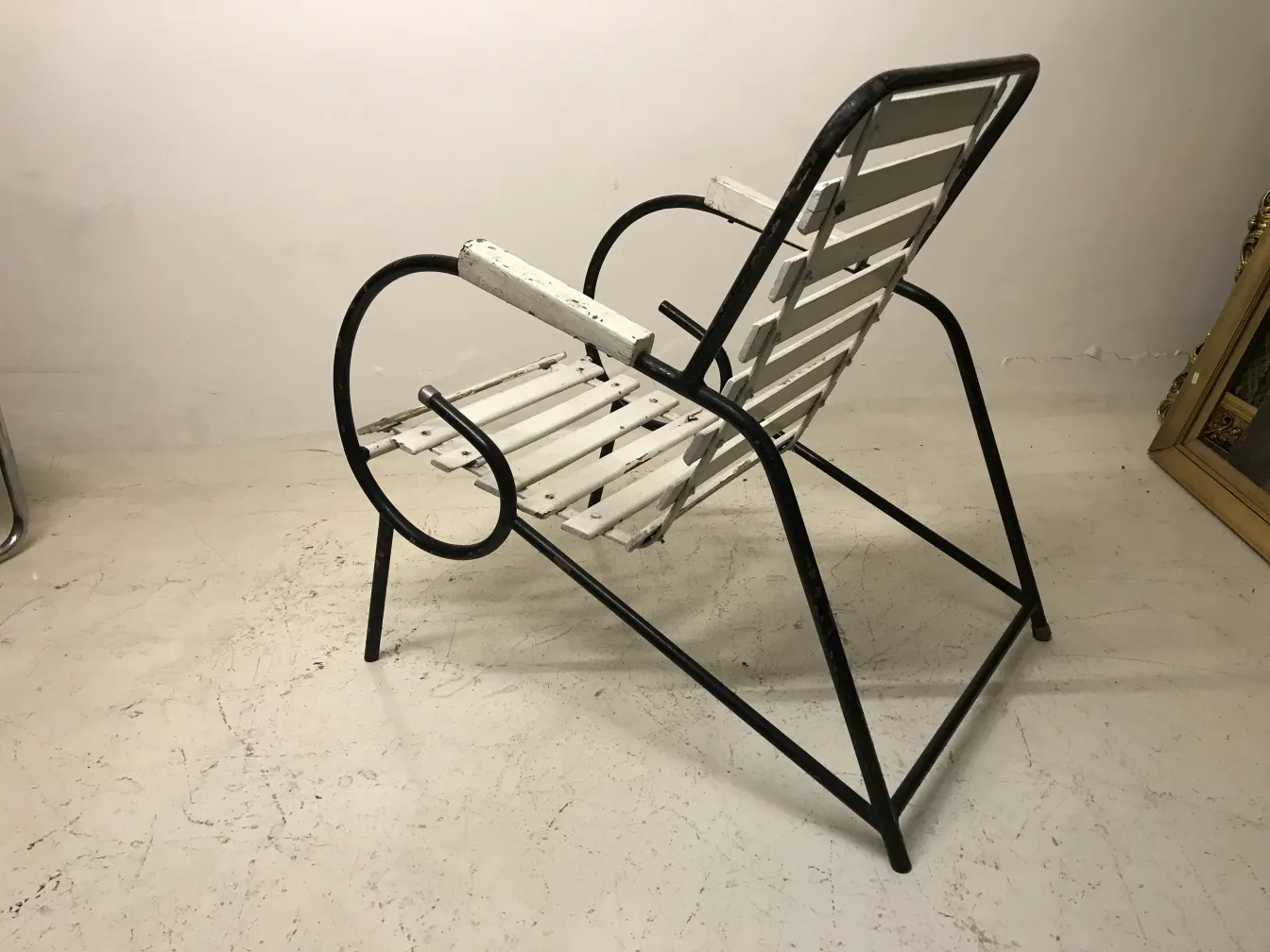 Sillones de jardín antiguos con acabado blanco y estructura en metal, en un ambiente neutro.