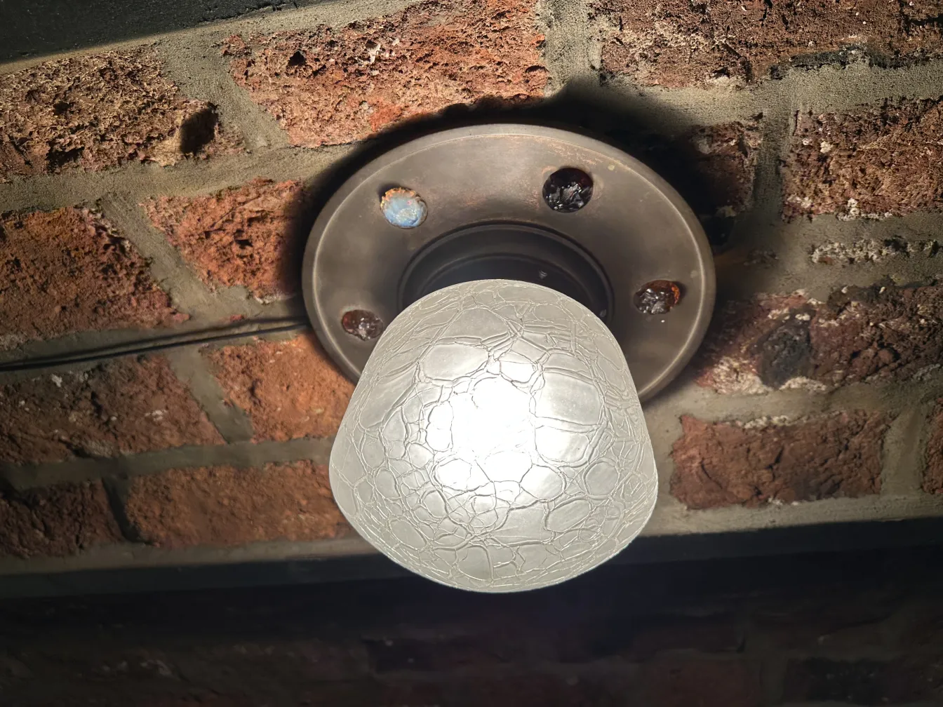 plafoniera con lampadina bianca su soffitto in mattoni