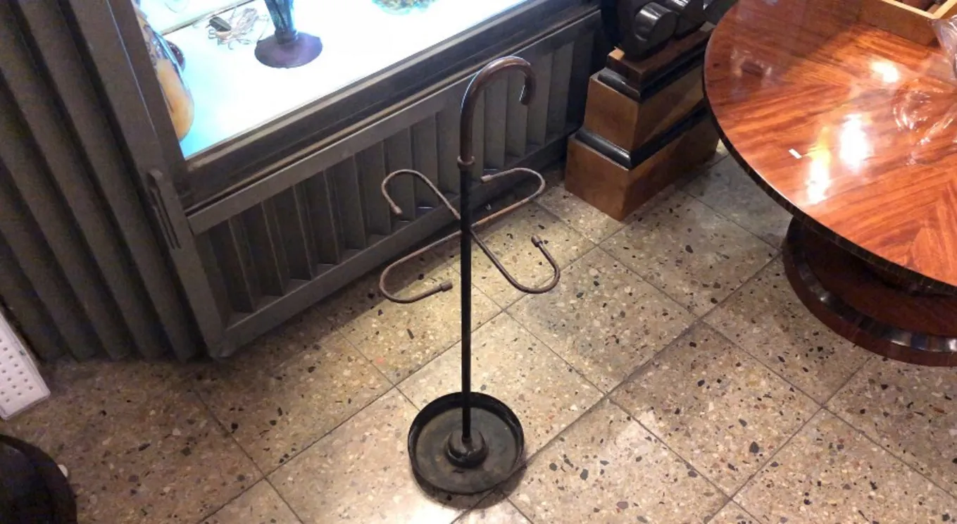 Porte-parapluie ancien avec un design décoratif dans un cadre classique.