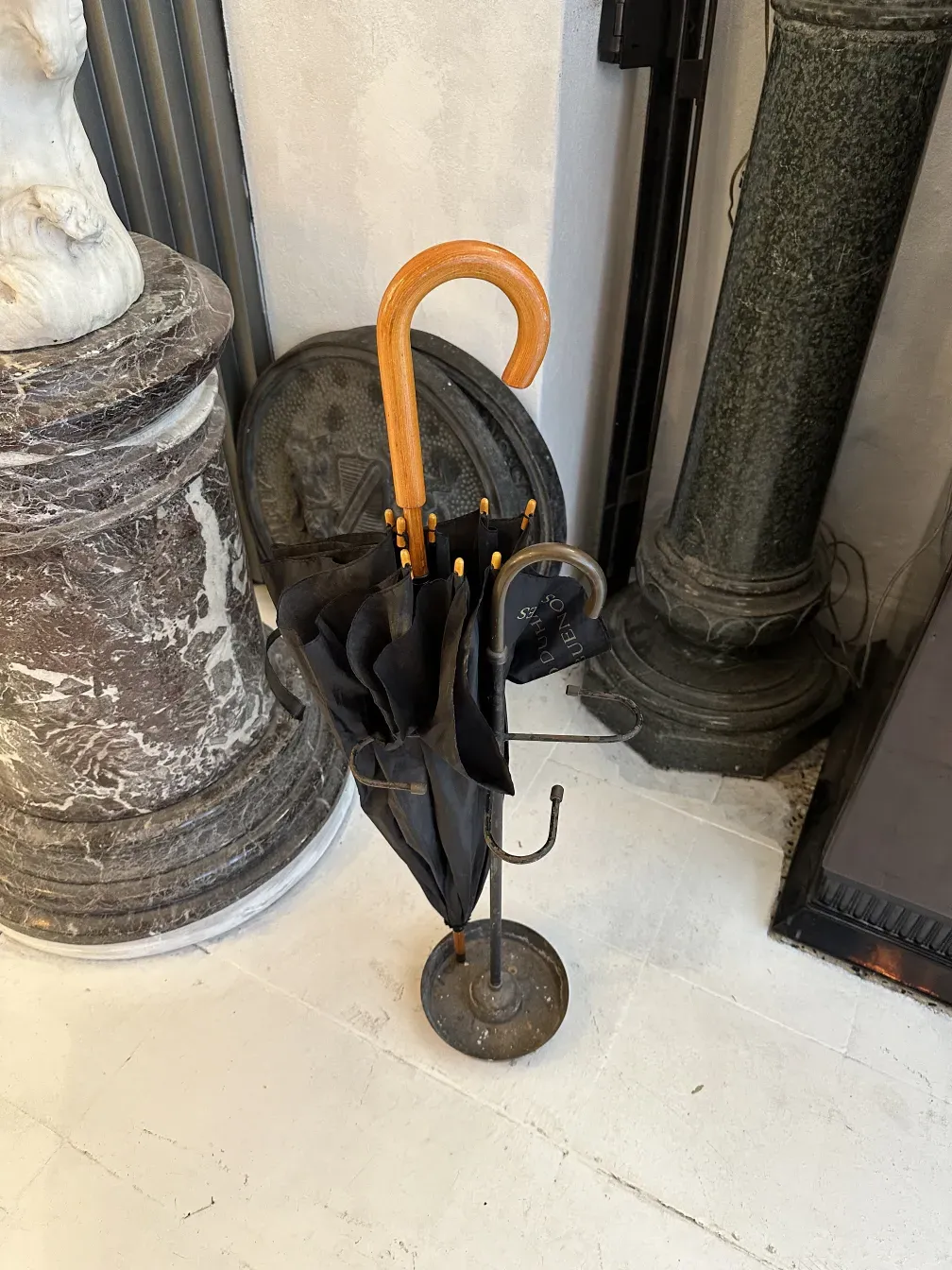 Porte-parapluie ancien avec parapluie noir et poignée en bois dans un cadre décoratif