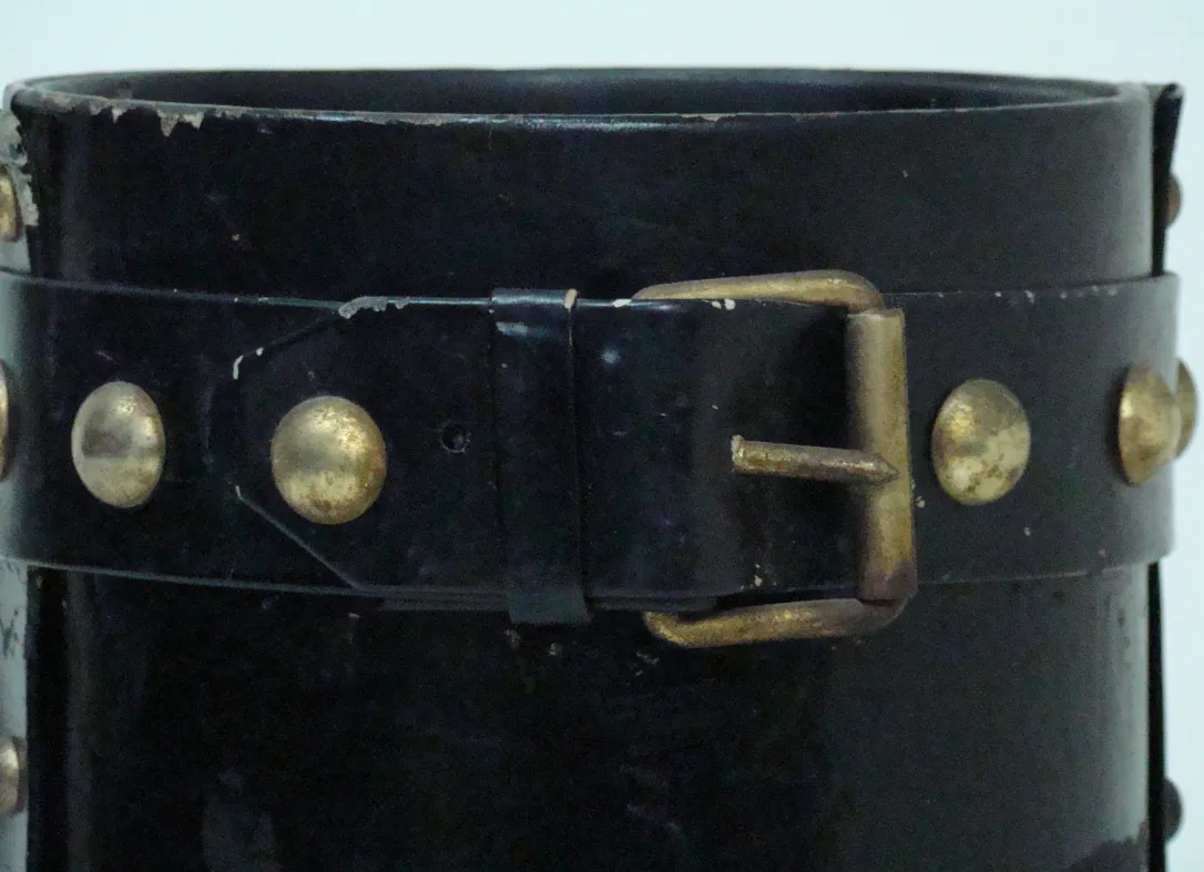 Antiguo paragüero negro con detalles dorados y diseño clásico.