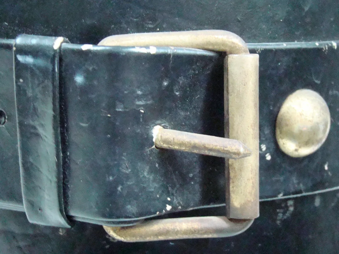 Suporte para guarda-chuva antigo com detalhe de fivela e fundo escuro