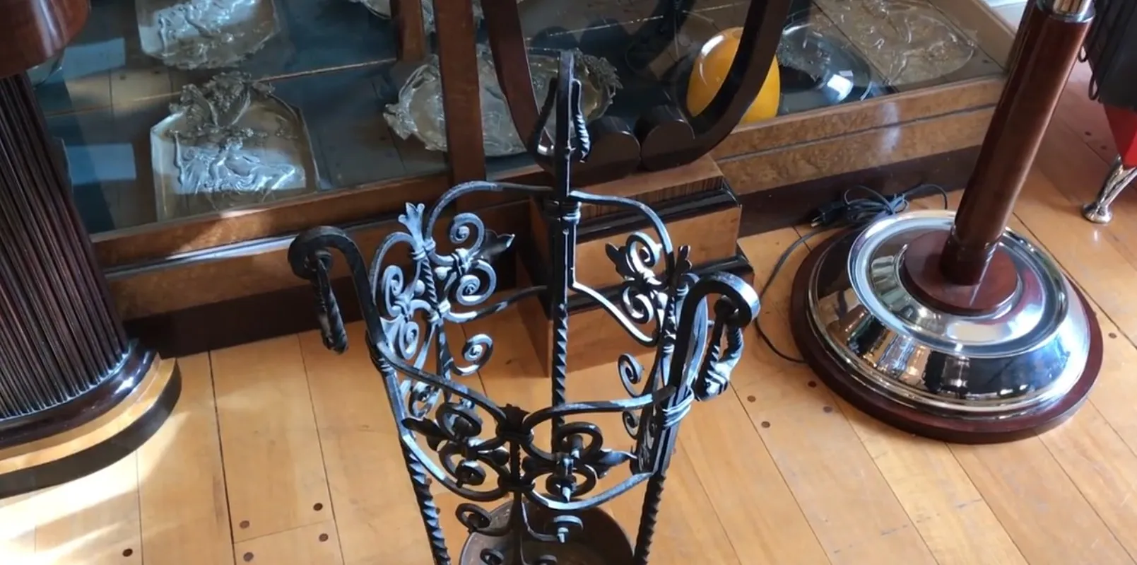 Antiker Schirmständer mit kunstvollem Eisen-Design in Schwarz, in einer eleganten Umgebung mit Antiquitäten.