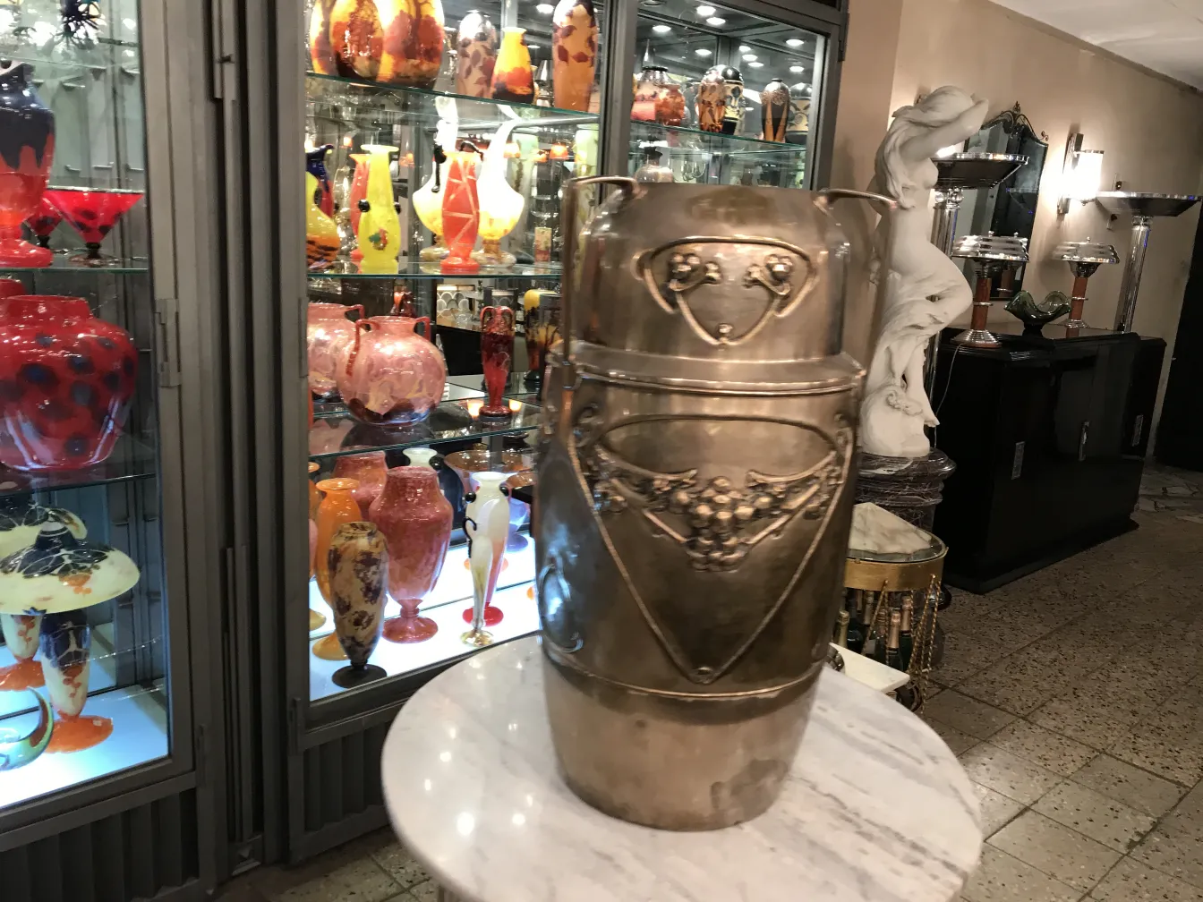 suporte para guarda-chuva antigo kayser com detalhes decorativos em um ambiente de antiguidades