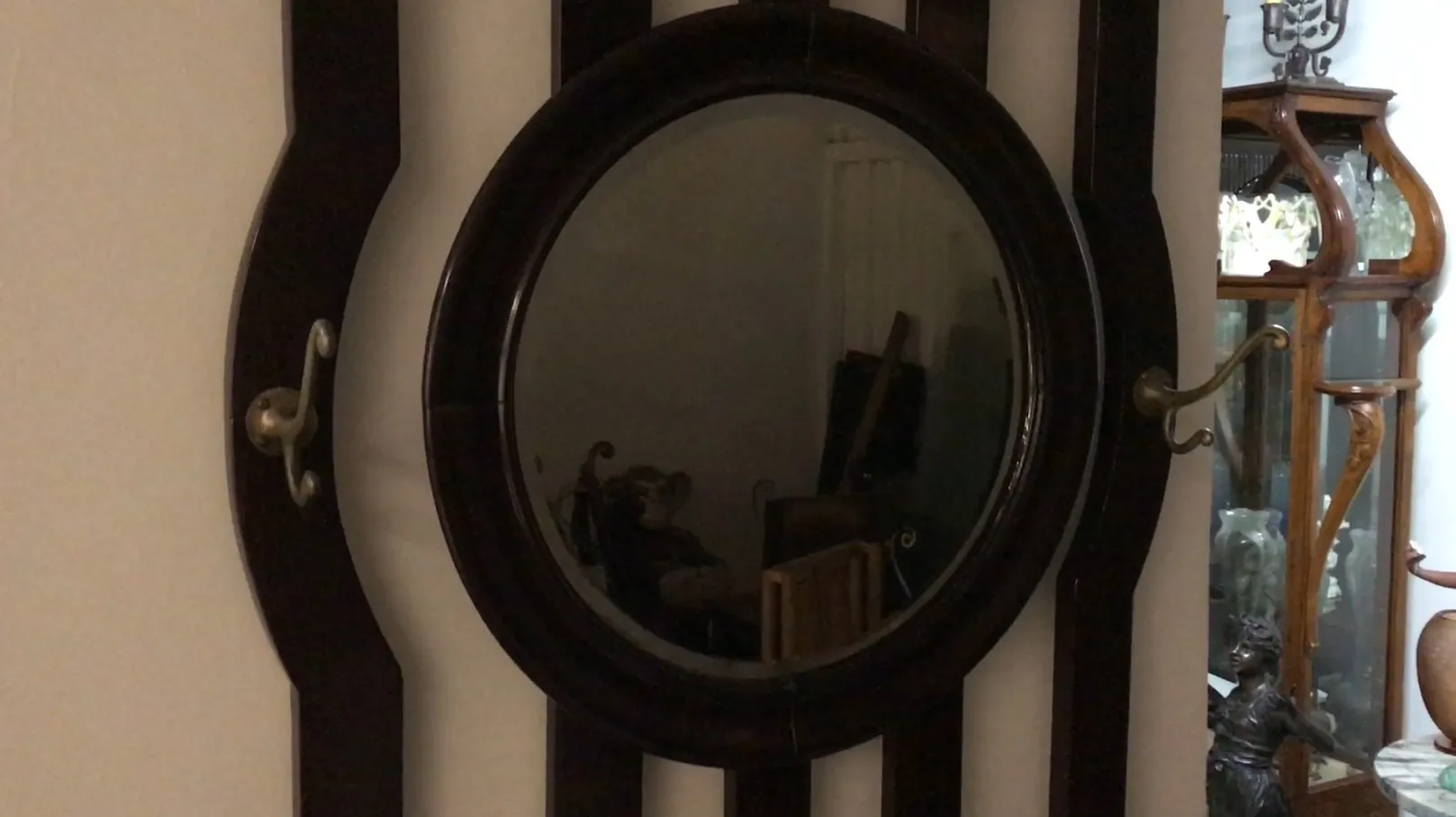 Bengaleiro antigo com espelho e ganchos decorativos na parede.