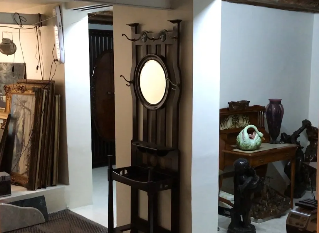 Antique coat rack with mirror and hooks in a classic setting.