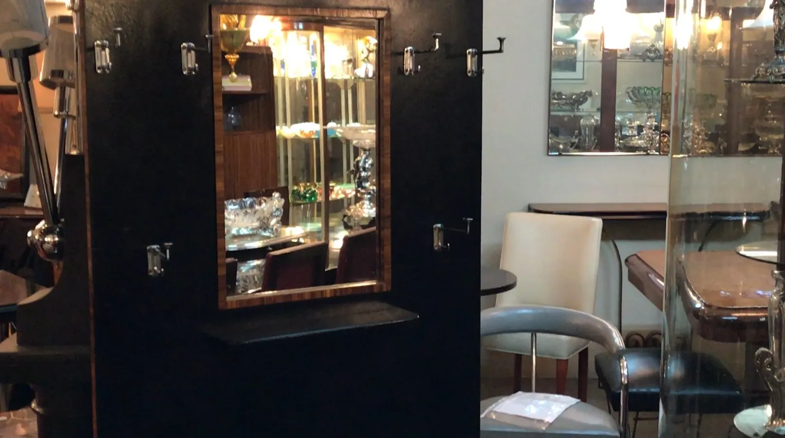 perchero antiguo negro con espejo y varios ganchos, en un ambiente clásico