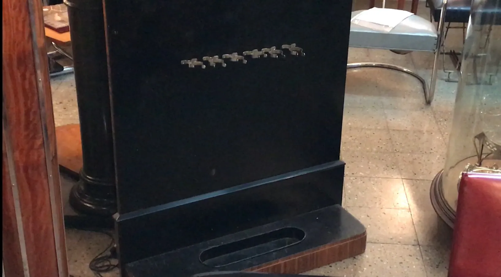 старинная вешалка темного цвета с крючками спереди, в окружении антиквариата