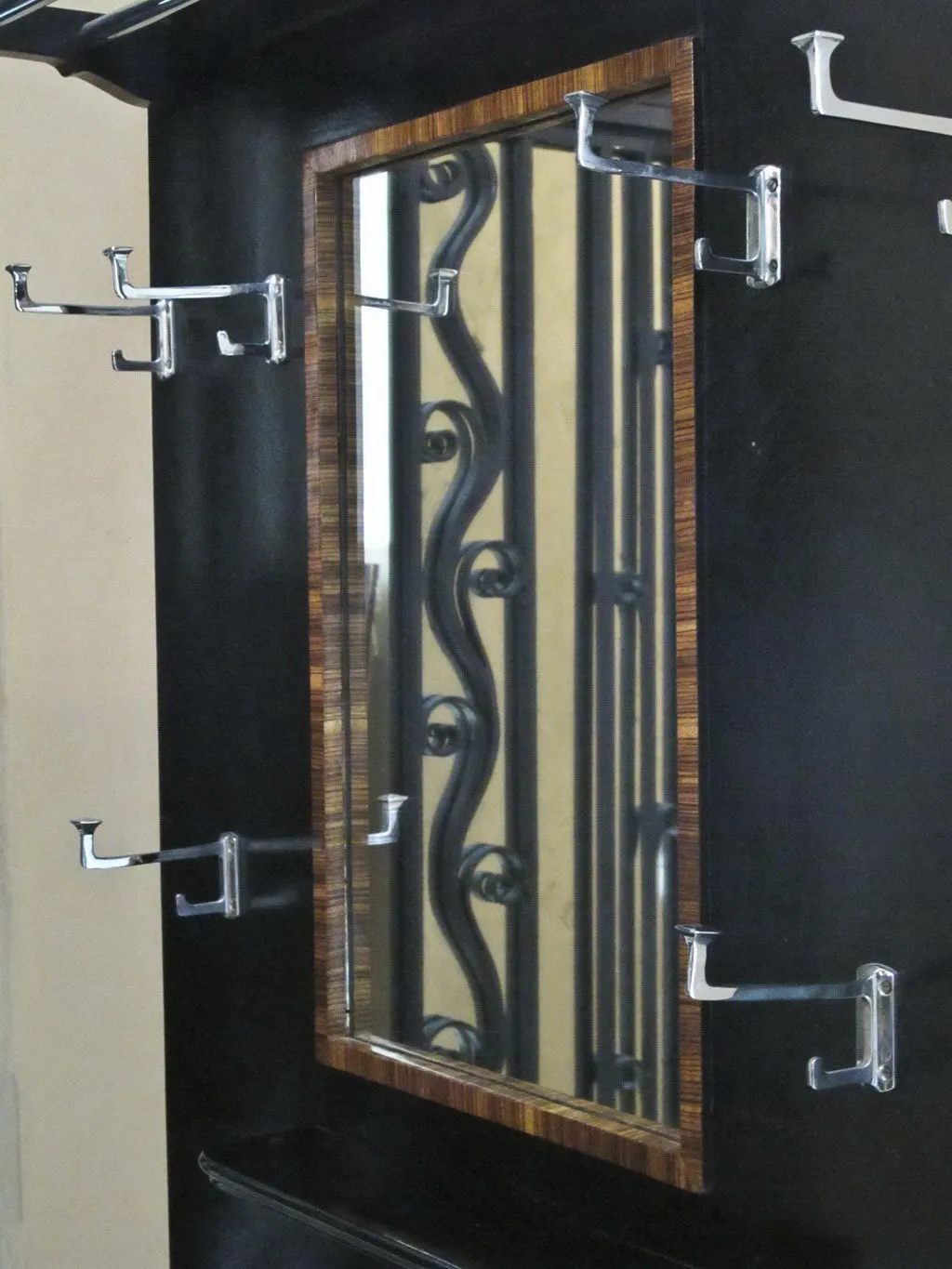 Antique coat rack featuring a mirror and multiple hooks in a classic setting.