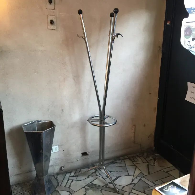 Antiker garderobenständer mit haken und rundem fuß. Wand hintergrund und steinboden.