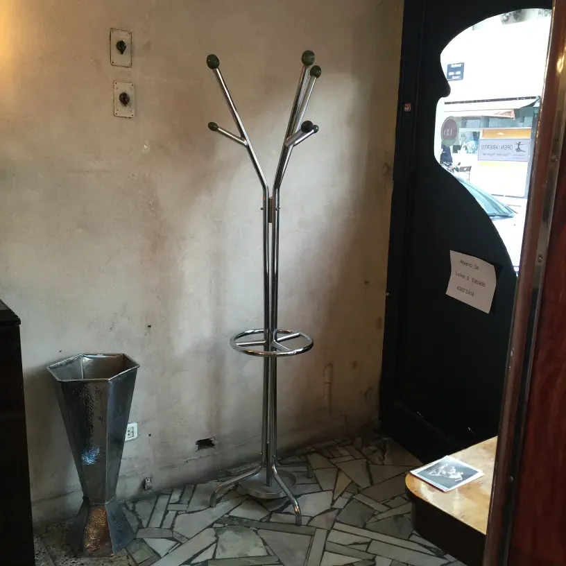 perchero antiguo de pie con detalles en verde, en un ambiente rústico