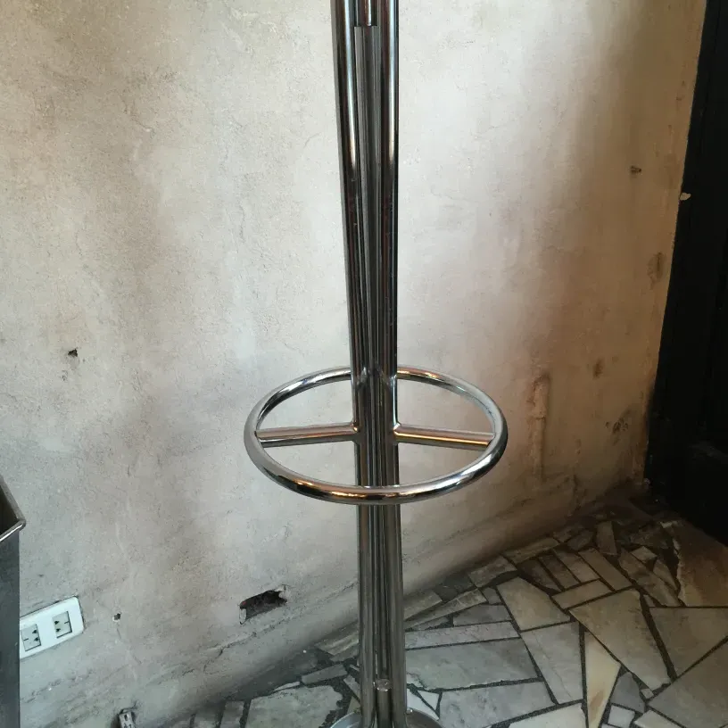 perchero antiguo con estructura metálica brillante, fondo neutro