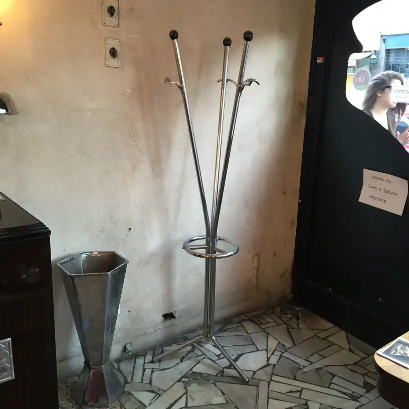 Portemanteau ancien au design élégant, avec crochets et base ronde dans un environnement neutre