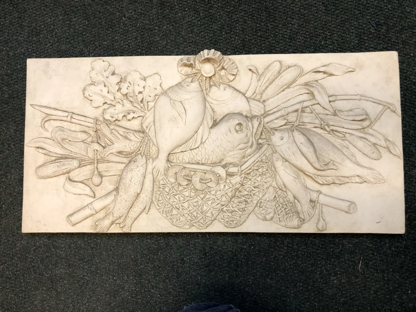 古いウォールプレートには野菜と魚の彫刻があります。