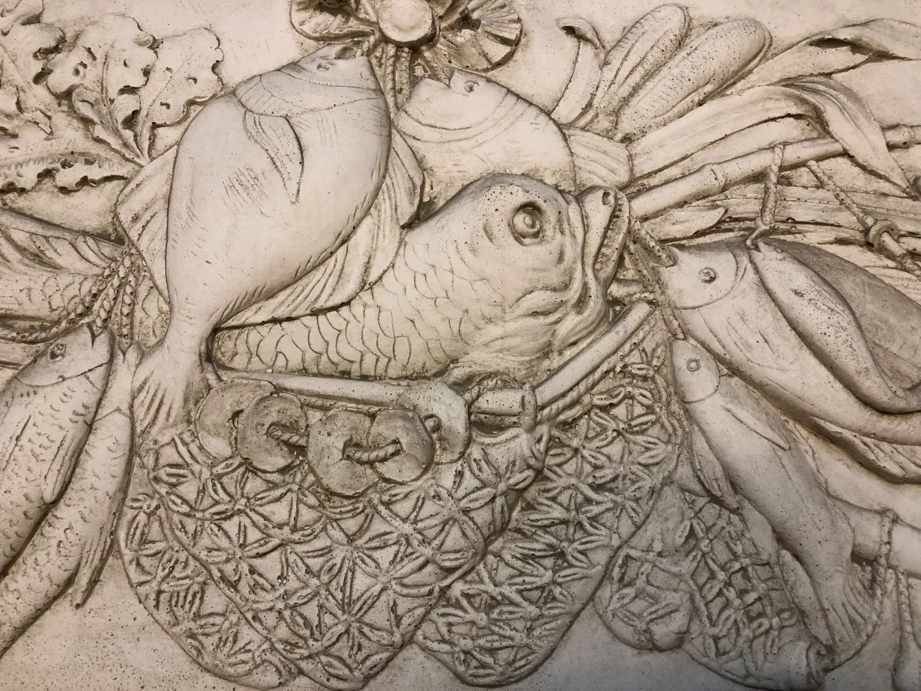 detail einer alten Wandplatte mit Fischen und Dekor