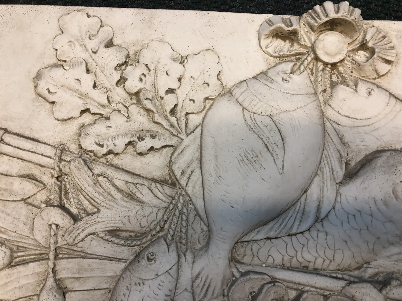 Plaque murale ancienne avec un design de poissons et de feuilles, affichant des détails élaborés, idéale pour la décoration