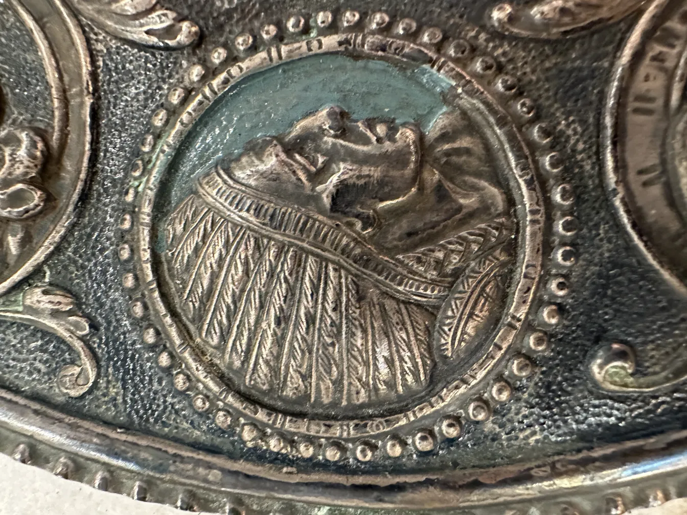 Detail of an antique wall plate featuring intricate relief details and a unique design.