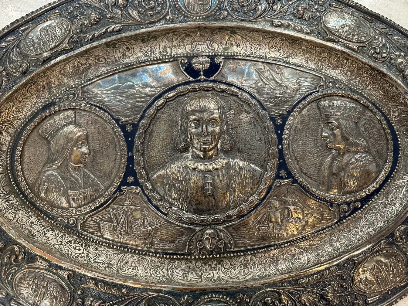 Antique wall plate featuring decorative portraits and ships.