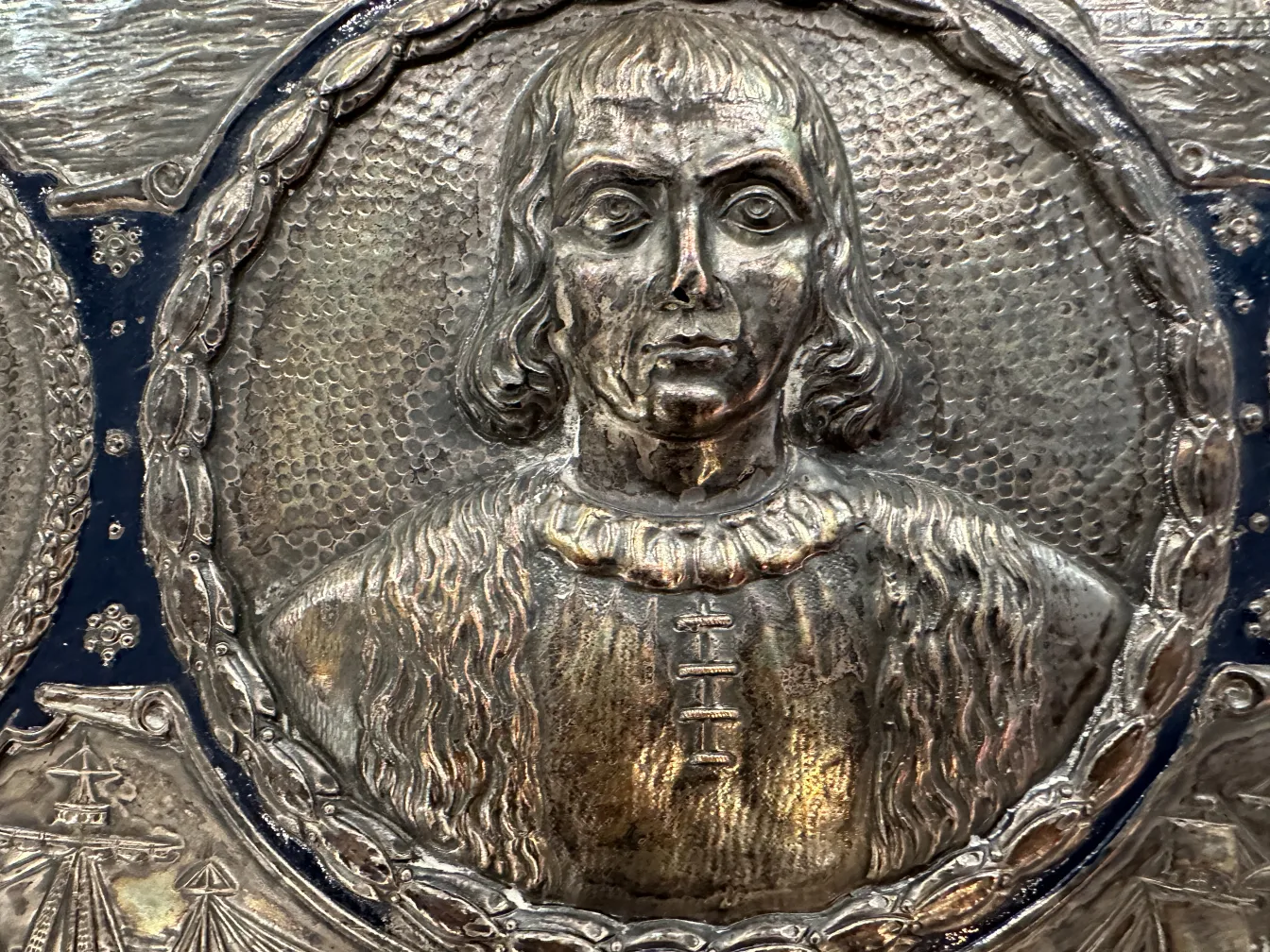 Antigua placa de pared con un retrato en relieve y detalles decorativos.