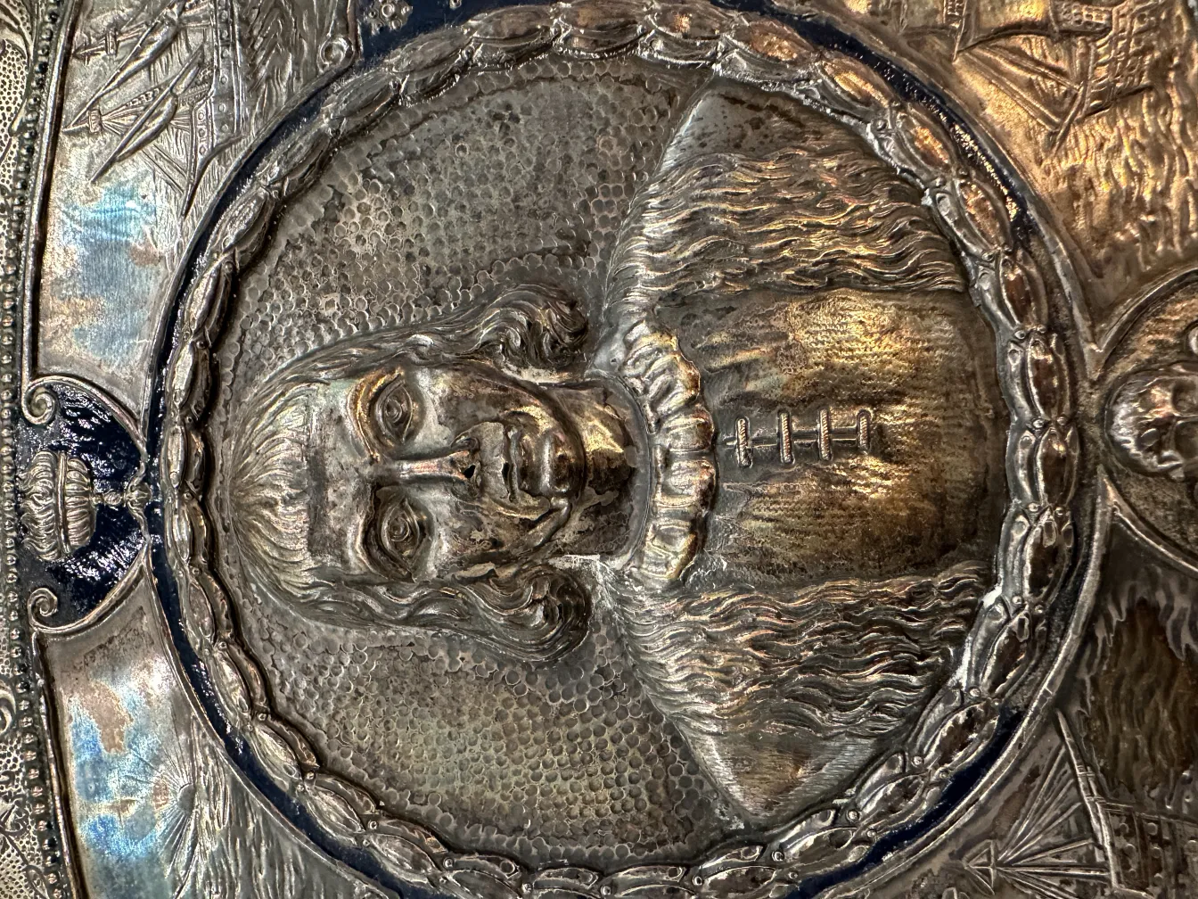 Antique wall plate featuring a carved portrait, ornamental details, soft background.