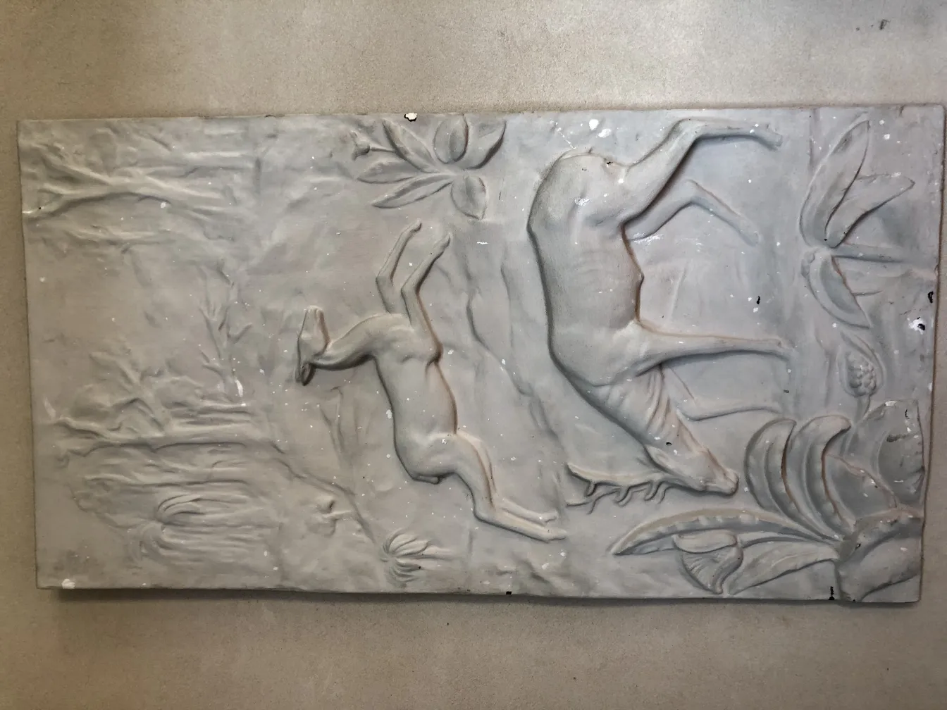 Placa de pared antigua con relieve de ciervos y plantas.