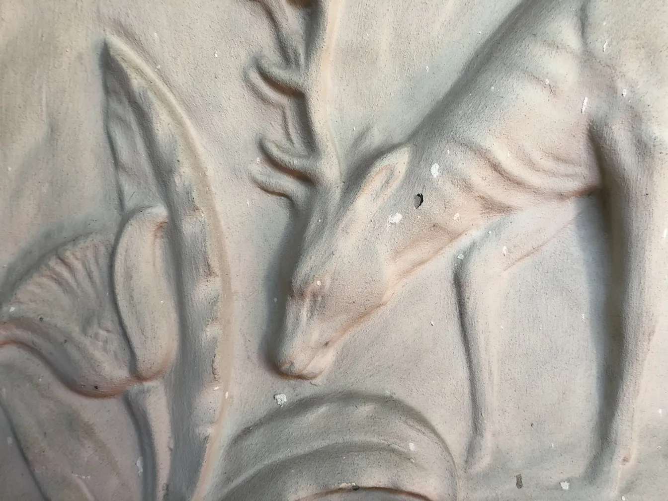detail of an antique wall plate featuring deer relief among leaves