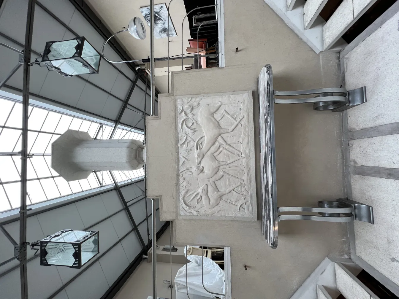 Placca a muro antica con rilievo e motivi decorativi, con luce ambientale intorno.